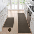 Two brown, waterproof, non-slip textured kitchen mats on a light wood floor in a white kitchen.