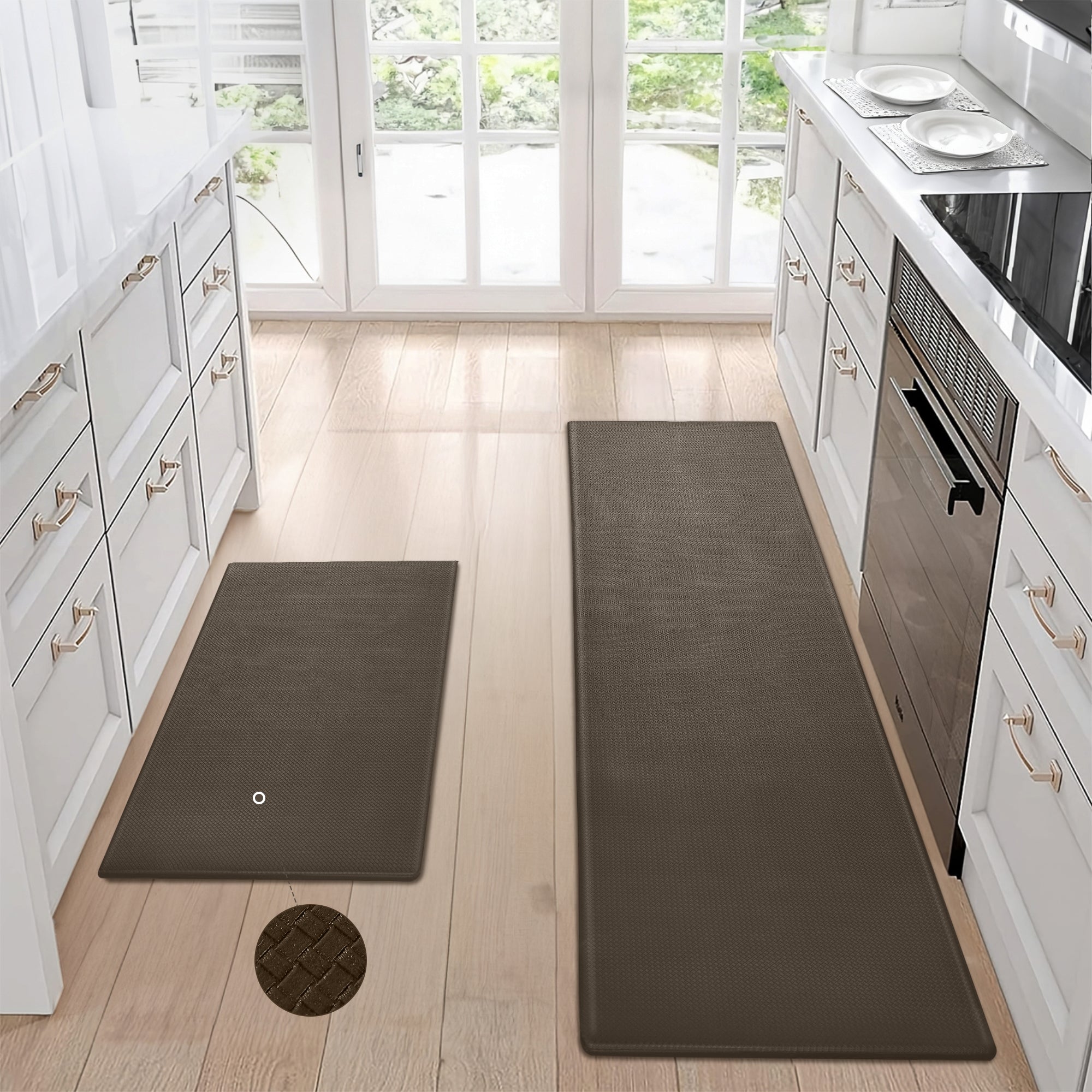 Two brown, waterproof, non-slip textured kitchen mats on a light wood floor in a white kitchen.