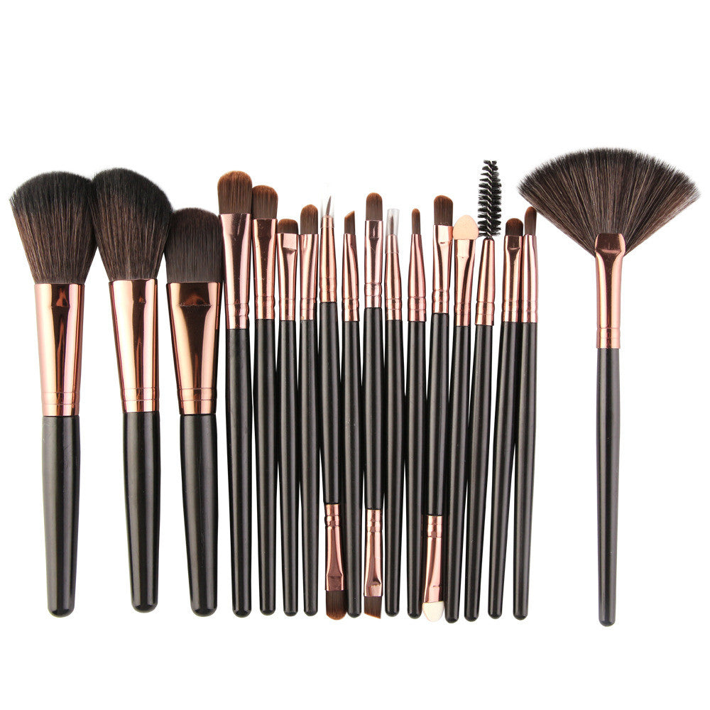 Set of makeup brushes with black handles, rose-gold ferrules, and dark brown bristles, including a fan brush.