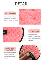 Pink circular makeup puff with soft, textured fiber, black trim, and finger-strap lanyard. Reusable and gentle.