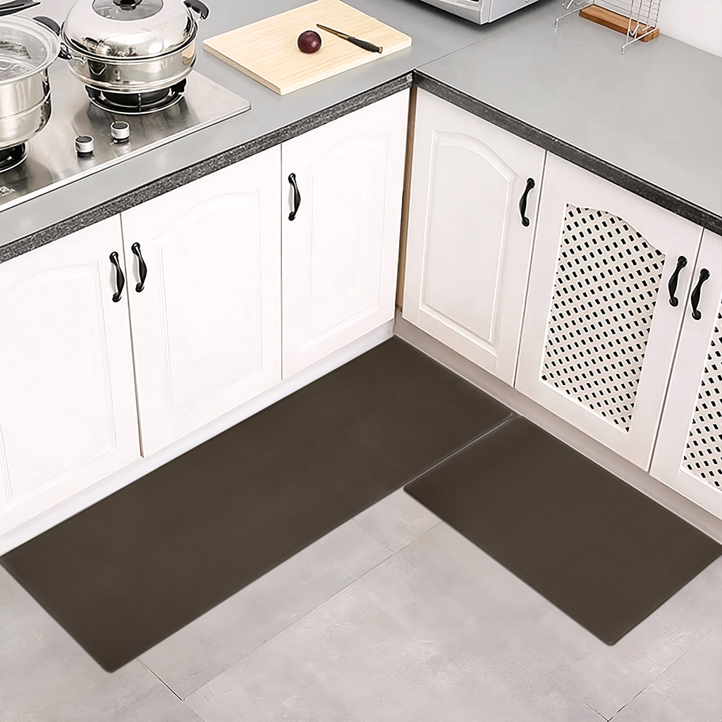 Two dark brown, waterproof kitchen mats on a tile floor in front of white cabinets. Practical, non-slip home decor.