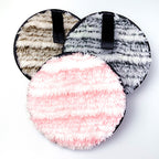 Three fuzzy, round cleansing makeup remover pads in pink, gray, and beige, each with a small black hanging loop.