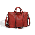 Large red leather tote bag with top handles, adjustable shoulder strap, and side zipper against a white background.
