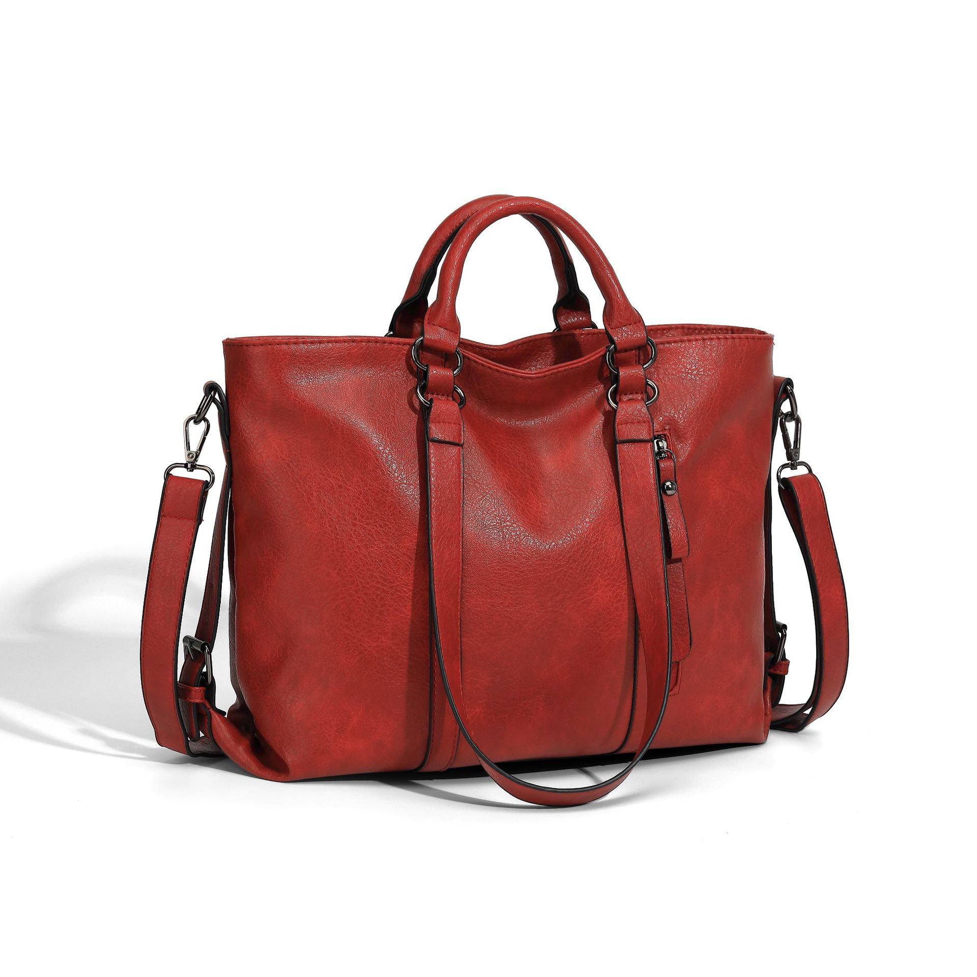 Large red leather tote bag with top handles, adjustable shoulder strap, and side zipper against a white background.