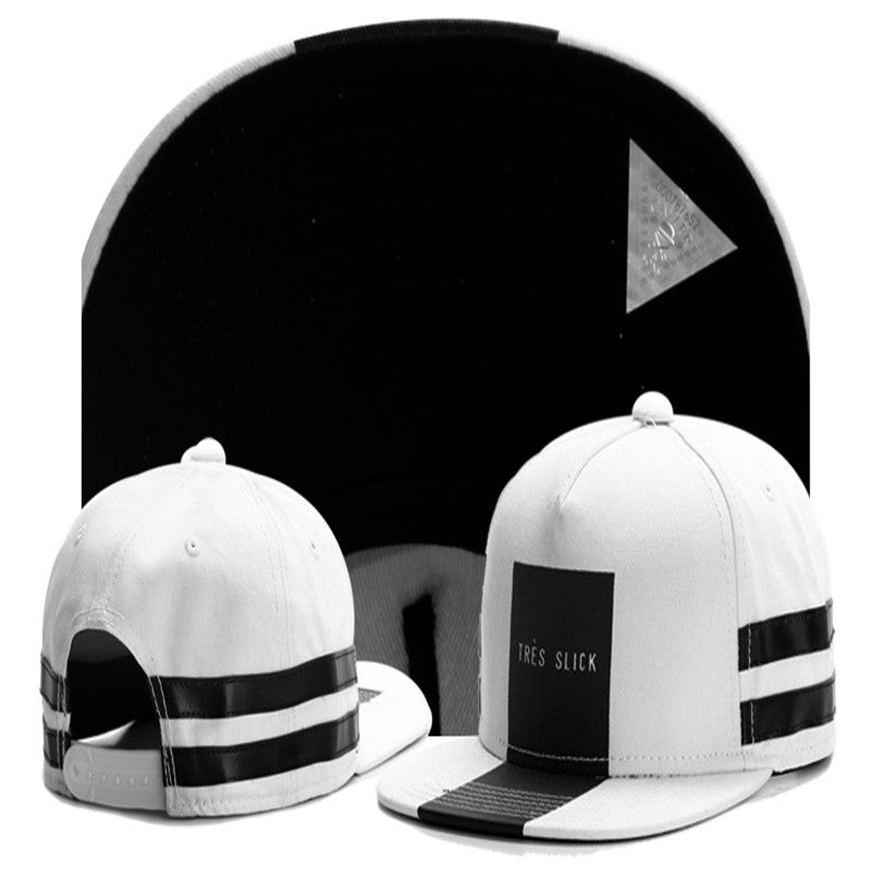 White and black hip-hop snapback hat with "TRES SLICK" logo, flat brim, and side striped detail.