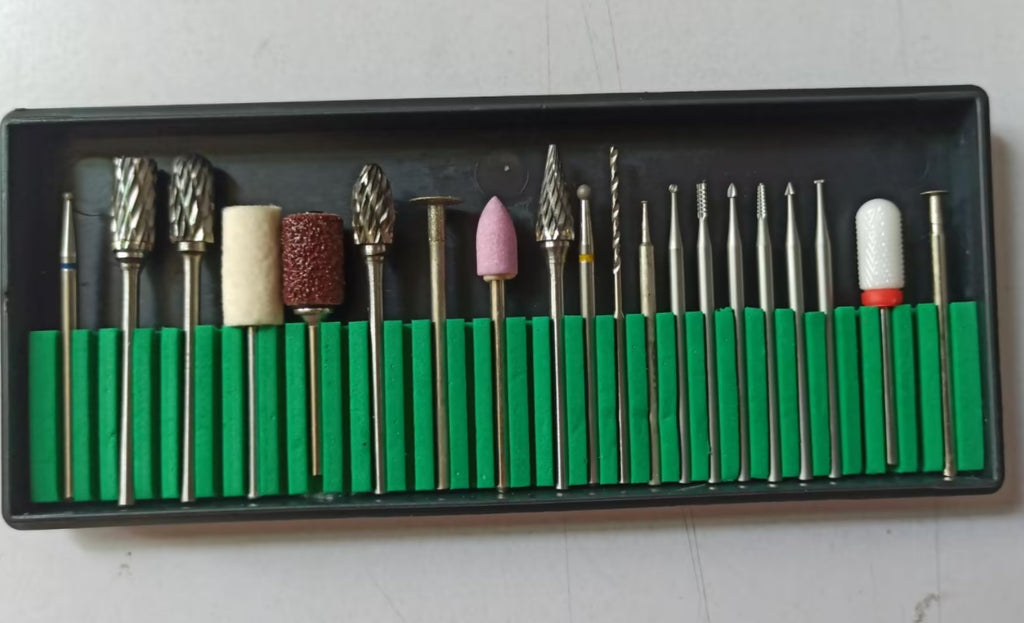 A set of diverse metal, stone, and abrasive grinding bits organized in a black case with a green foam holder.