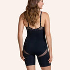 A model wearing a black, hip-lifting, body-sculpting bodysuit with lace trim, mesh accents, and thin straps.