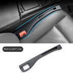 Black matte plastic car seat gap organizer inserted between the console and leather seat. Includes seat belt slot.