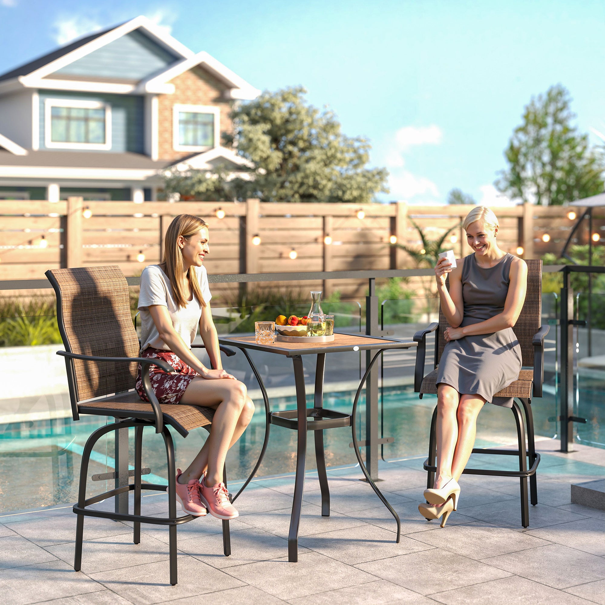 Two brown, sling-fabric outdoor swivel bar stools with black metal frames and armrests by a patio table near a pool.