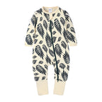 Cream-colored baby cotton onesie with a black leaf print, featuring long sleeves and a full-length front zipper.