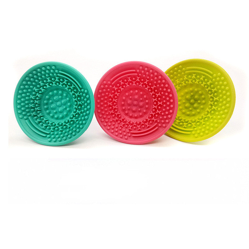 Three round, silicone makeup brush cleaning pads in teal, pink, and lime green with textured, scrubby surfaces.