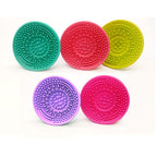 Five colorful silicone makeup brush cleaning pads with textured surfaces for scrubbing, arranged on a white background.
