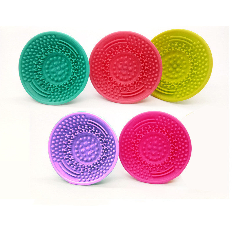 Five colorful silicone makeup brush cleaning pads with textured surfaces for scrubbing, arranged on a white background.