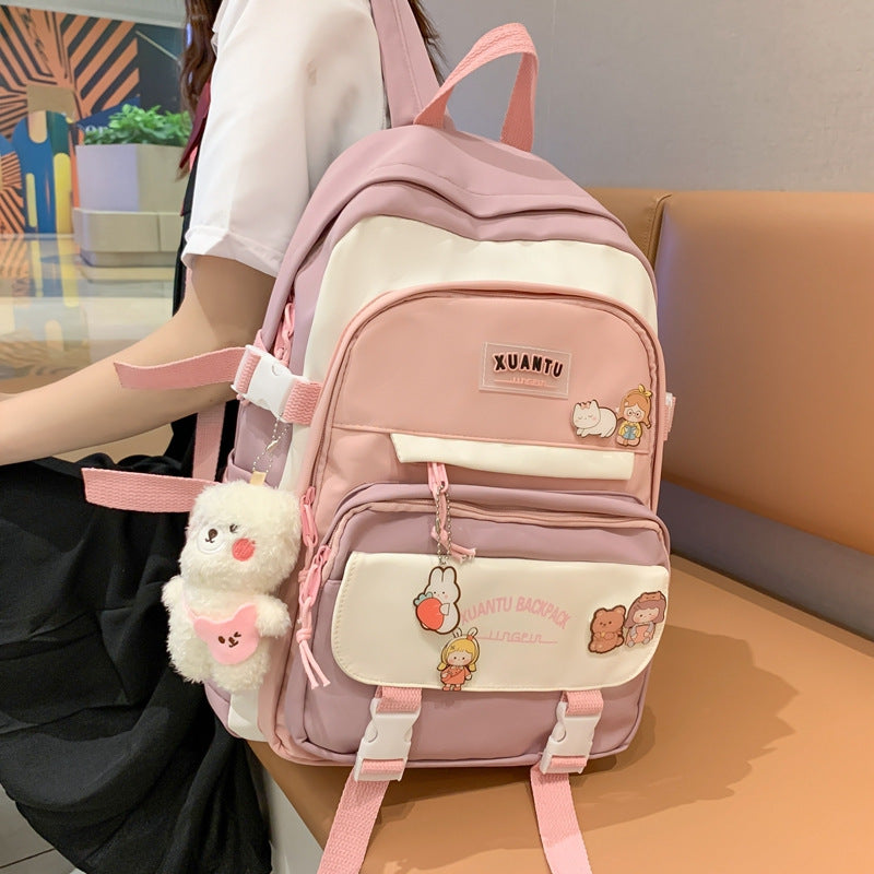 Pink and cream Korean-style backpack with multiple pockets, buckles, cute character pins, and a fluffy bear charm.