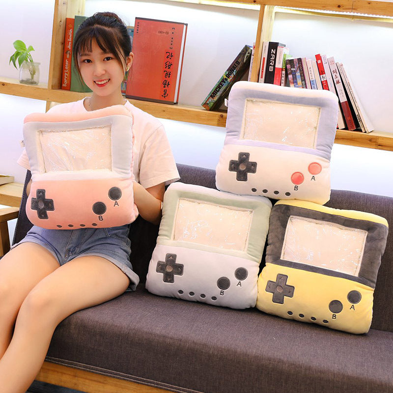 Woman holding a plush, pastel-colored retro gaming console pillow with a clear hand-warming sleeve feature.