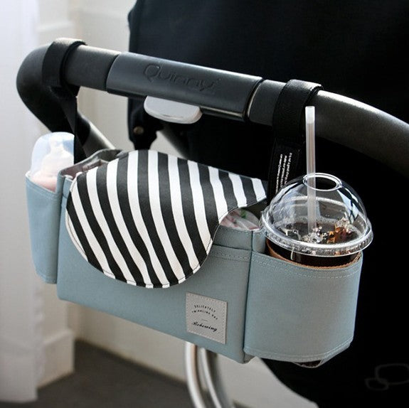 Light blue fabric baby stroller organizer with black and white striped flap, side cup holders, and Velcro straps.