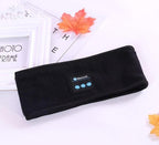 Black fleece Bluetooth headband with control panel, placed on a white background with decorative autumn leaves.