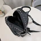 Black soft leather backpack with skull embossing, silver rivet studs, top handle, and adjustable shoulder straps.