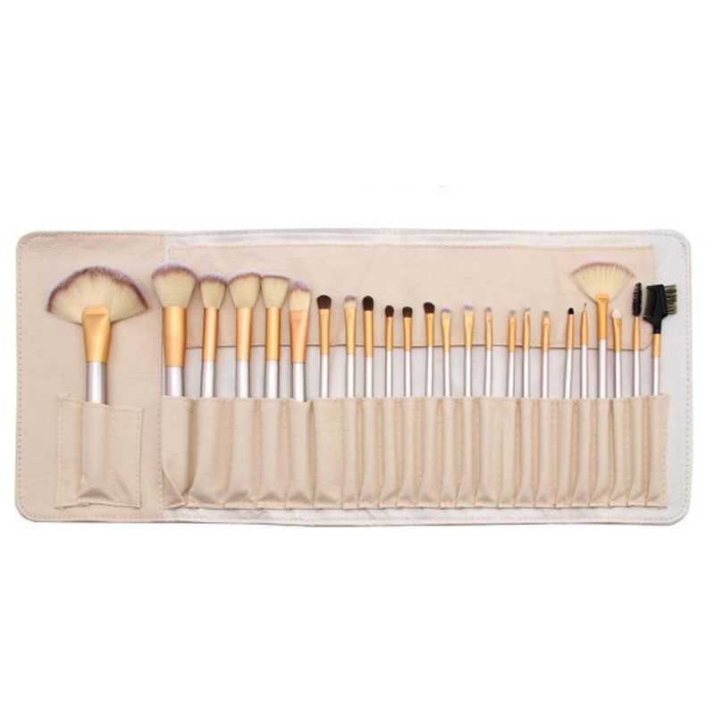 Set of 24 champagne-handled synthetic makeup brushes with creamy white bristles, arranged in a matching leatherette roll.