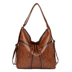 Brown soft leather convertible shoulder bag and backpack with decorative front zippers and tassels, isolated on white.