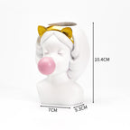 White resin vase shaped like a girl with a pink bubblegum bubble and gold cat-ear headband. 10.4cm tall.