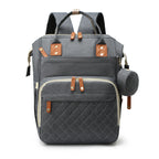 Grey quilted mummy backpack with tan leather accents, top handles, multiple compartments, and a matching side pouch.