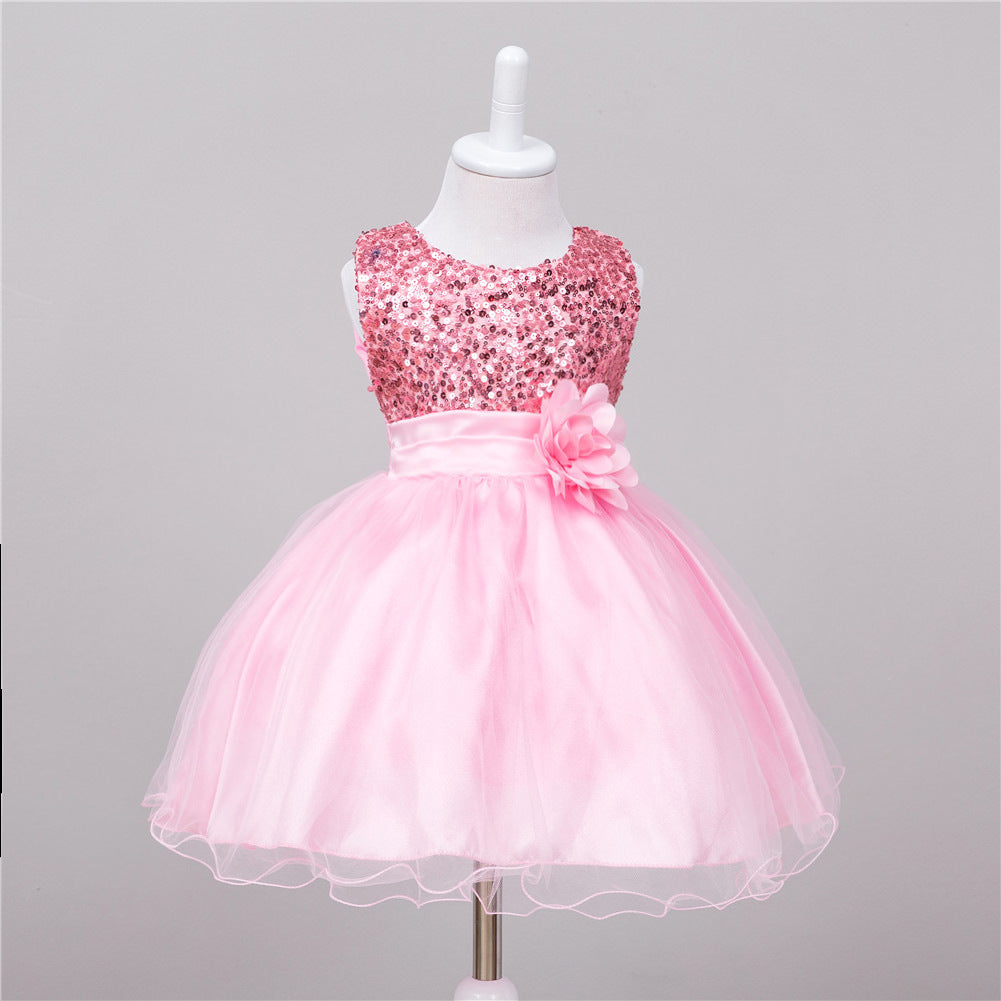 Pink baby dress featuring a sequin bodice, satin waistband with a flower accent, and a layered tulle tutu skirt.