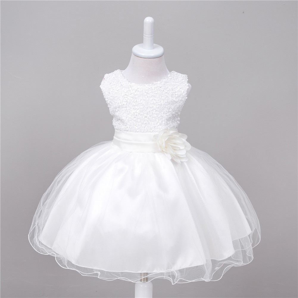 White baby flower girl dress with sequin bodice, satin waistband, and full tulle skirt featuring a floral accent.