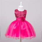 Fuchsia baby dress with sequin bodice, satin waistband with floral accent, and a layered tulle skirt on a mannequin.
