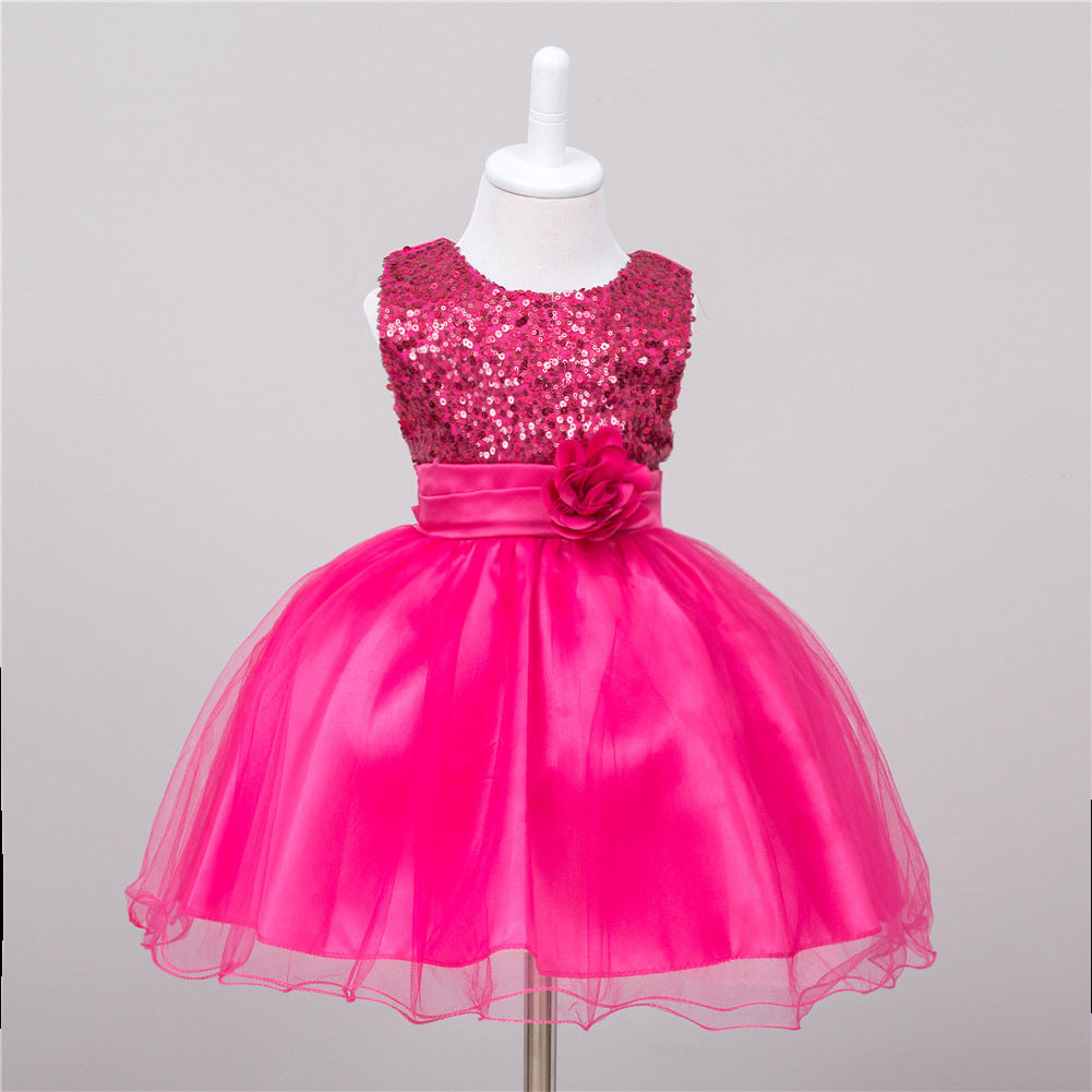 Fuchsia baby dress with sequin bodice, satin waistband with floral accent, and a layered tulle skirt on a mannequin.