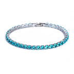 A silver tennis bracelet micro-inlaid with round, vibrant cyan zircon stones against a white background.