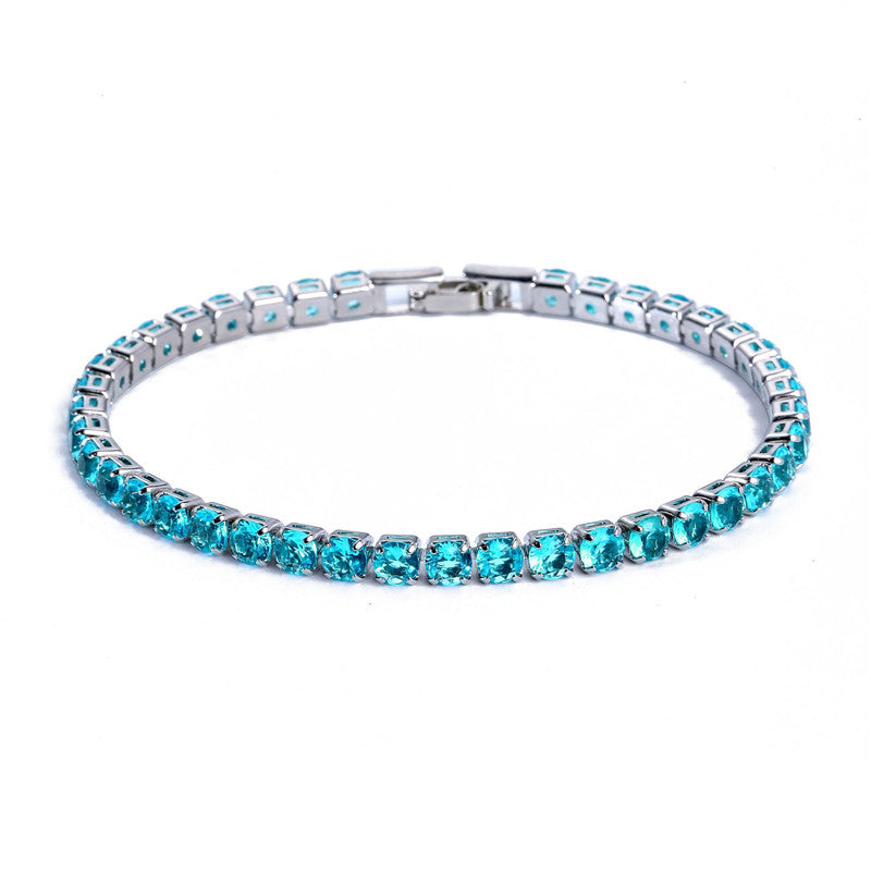 A silver tennis bracelet micro-inlaid with round, vibrant cyan zircon stones against a white background.
