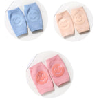 Blue, peach, and pink terry cloth baby knee pads with silicone smiley faces, arranged in three circular sets.