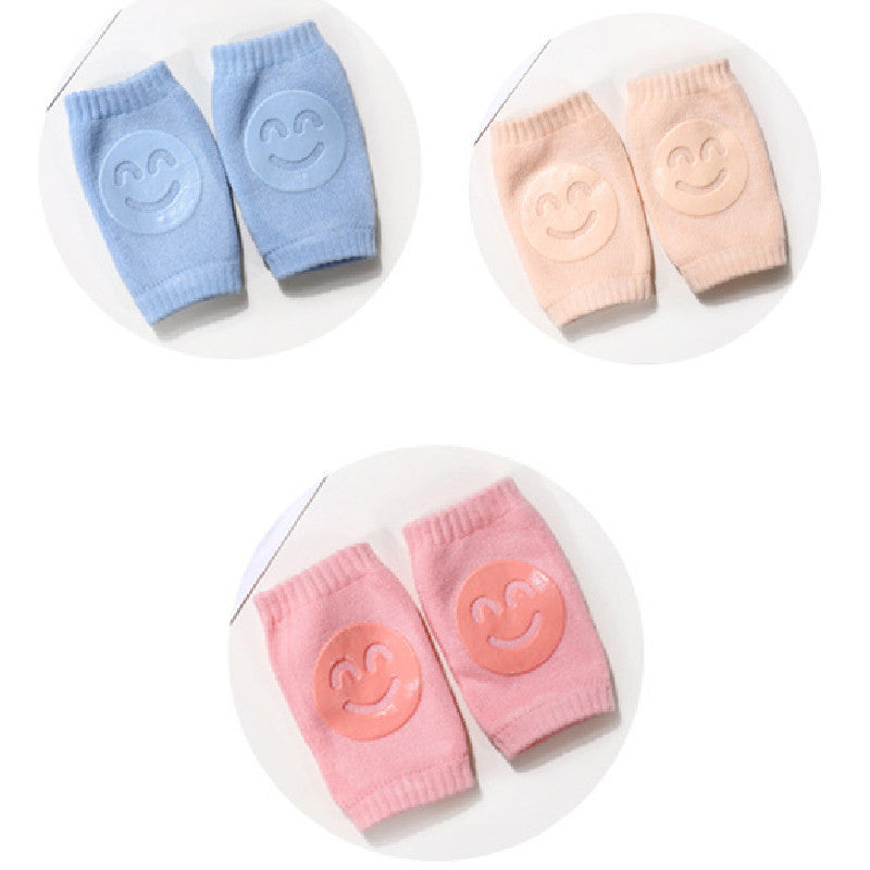 Blue, peach, and pink terry cloth baby knee pads with silicone smiley faces, arranged in three circular sets.