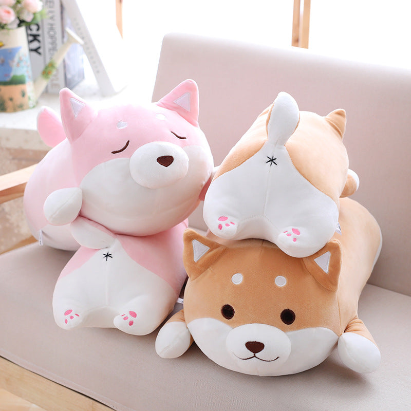 Soft, plush pink and brown Shiba Inu dog pillows with cute embroidered details, sitting together on a beige sofa.