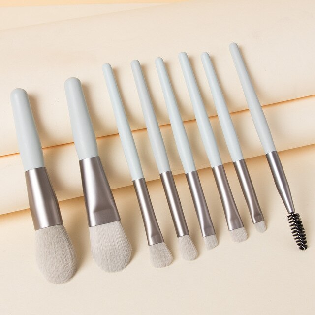 Digitaldistribution375 set of 8 mini makeup brushes with soft gray handles and metallic ferrules on a cream background.