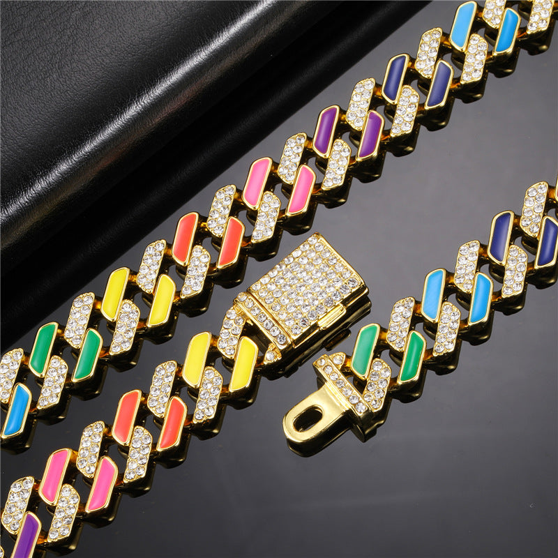 Gold-tone Cuban link chain with multicolored enamel accents and pavé rhinestones, featuring a secure clasp.