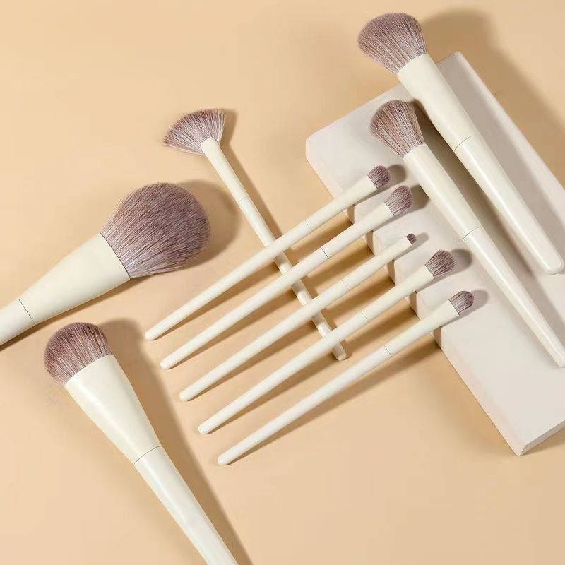 Set of cream-colored makeup brushes with soft, two-toned synthetic bristles on a matching beige background.