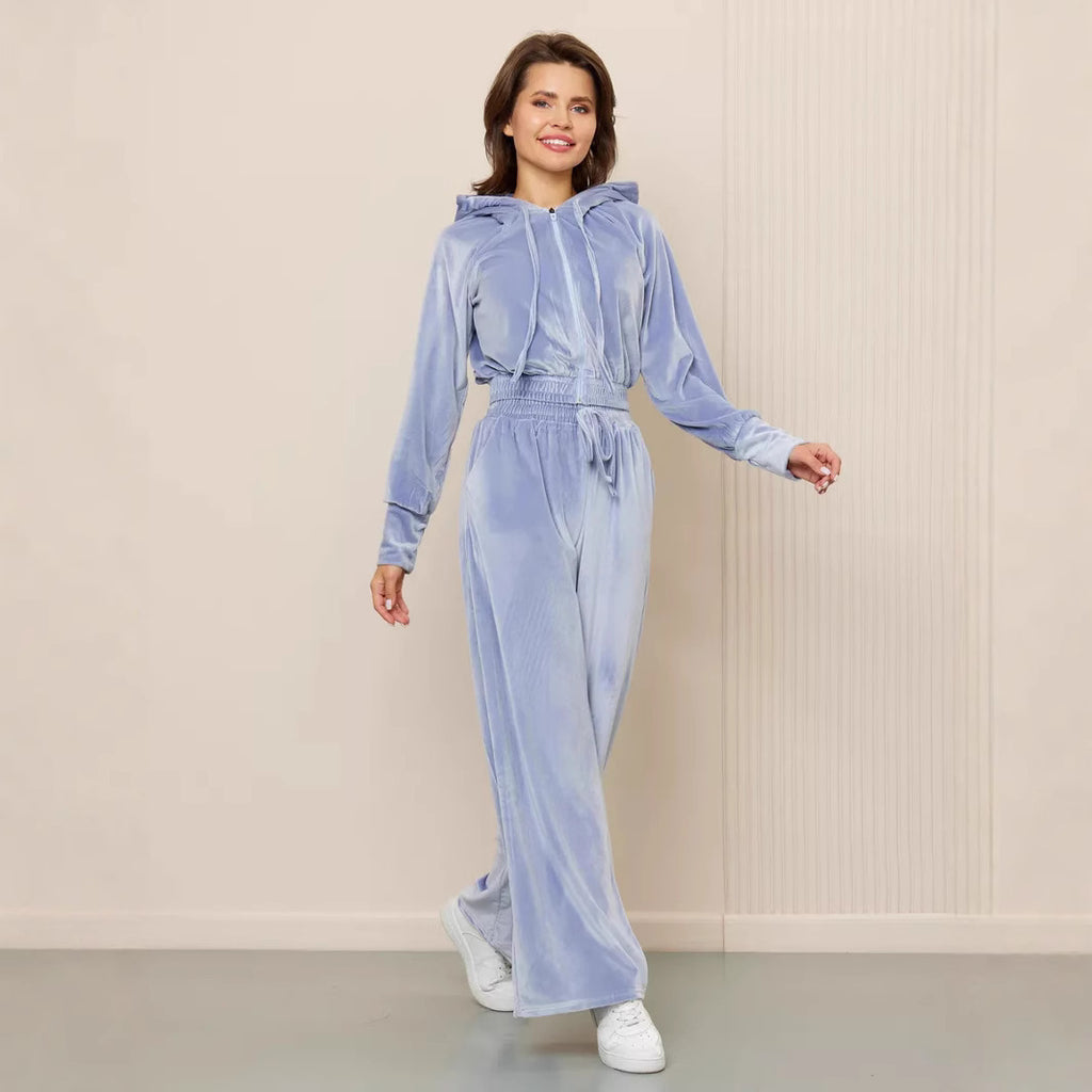 Woman wearing a light blue velvet zip-up hooded jacket and matching wide-leg drawstring trousers set.