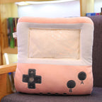 Soft pink plush hand warmer pillow shaped like a vintage game console with a clear plastic screen pocket.