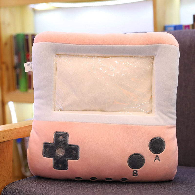 Soft pink plush hand warmer pillow shaped like a vintage game console with a clear plastic screen pocket.