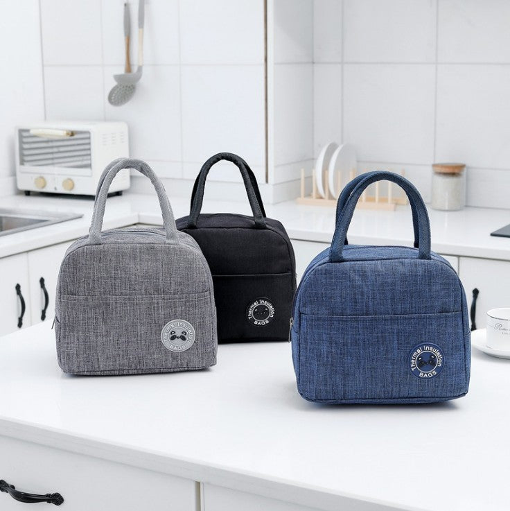 Three portable, cationic fabric thermal lunch bags in grey, black, and blue, each with a handle and front logo patch.