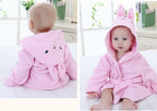 A baby wearing a soft, pink cotton hooded bathrobe with cute rabbit ears and embroidered animal face details.
