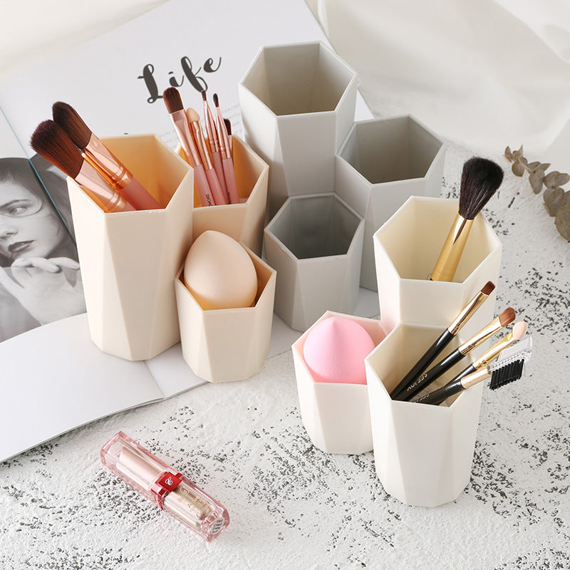 Beige and gray hexagonal makeup brush holders in various heights made of plastic, holding brushes and makeup sponges.