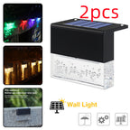 Two waterproof, black solar LED fence lights with bubble-textured clear housing, shown with RGB and warm light effects.
