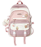 Pink and white Korean-style nylon backpack with buckle straps, character pins, and a plush bear charm.
