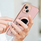 Pink phone case with gold electroplated trim and a 3D astronaut figure acting as a kickstand held in a person's hand.