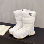 White mid-calf snow boots with a quilted cotton upper, side zipper, circular snowflake logo, and tan lug soles.