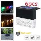 6-pack waterproof solar LED fence lights with black housing and clear, bubble-textured glass, displaying RGB colors.