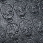 Close-up of black, textured soft leather embossed with a repeating skull pattern for a stylish, edgy backpack design.